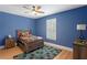 Vibrant bedroom featuring a wooden bed frame, blue walls, and window shutters at 4612 W Lowell Ave, Tampa, FL 33629