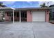 Charming pink single-story home featuring a covered carport and white garage door, complemented by tropical palm tree accents at 5445 Manatee Point Dr, New Port Richey, FL 34652