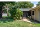A covered patio area with a brick walkway, lush landscaping, and view of the home's exterior at 606 Brentwood Pl, Brandon, FL 33511