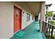 Hallway view leading to a unit with a bright orange door and cute decor at 6150 Gulfport S Blvd # 302, Gulfport, FL 33707