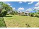 This backyard features plenty of green space with mature trees and manicured landscaping at 6436 Huntington Dr, Zephyrhills, FL 33542