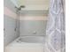 Bathroom featuring a tub, shower head, gray tiled walls, and a decorative shower curtain at 6436 Huntington Dr, Zephyrhills, FL 33542