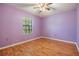 A minimalist bedroom features lilac walls, wood floors, and a ceiling fan at 6436 Huntington Dr, Zephyrhills, FL 33542