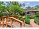 Charming backyard with a wooden bridge, lush landscaping, and a brick pathway leading to the home's entrance at 750 Alda Ne Way, St Petersburg, FL 33704
