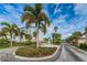Community entrance featuring mature trees, manicured landscaping, and an elegant water fountain at 8 Glencoe Pl # 305, Dunedin, FL 34698