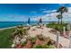 Relax outdoors on this patio with seating, umbrellas, and beautiful landscaping with stunning water views at 8 Glencoe Pl # 305, Dunedin, FL 34698