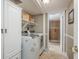 Convenient laundry room with washer, dryer, shelving and doorway to bathroom at 8240 144Th Ln, Seminole, FL 33776