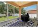 Relaxing screened-in lanai featuring an outdoor grill, ceiling fan, and comfortable seating area at 9917 Prevatt St, Gibsonton, FL 33534