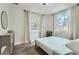 Sunlit bedroom with hardwood floors, neutral-toned walls, and two windows dressed in flowing, light-colored curtains at 1145 53Rd N Ave, St Petersburg, FL 33703