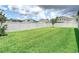 View of large backyard with bright green lawn and surrounding homes beyond white vinyl fence at 12687 Retreat Pl, Spring Hill, FL 34610
