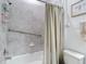 Bathroom featuring a shower with curtain, grab bar, and tiled walls, ensuring safety and accessibility at 12687 Retreat Pl, Spring Hill, FL 34610