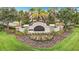 Community entrance featuring manicured flowerbeds, lush green lawn, and stone accents at 12687 Retreat Pl, Spring Hill, FL 34610