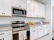 Modern kitchen featuring stainless steel appliances, granite countertops, and white cabinets at 12687 Retreat Pl, Spring Hill, FL 34610