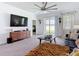 Bright living room with a decorative ceiling fan, large TV, and sliding glass door to the backyard at 12687 Retreat Pl, Spring Hill, FL 34610