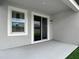 View of covered patio with sliding glass doors and light gray concrete floor and stucco walls at 12687 Retreat Pl, Spring Hill, FL 34610