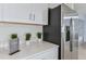 Modern kitchen with stainless steel refrigerator, white countertops, cabinets, and plants as decor at 13548 Tropical Breeze Way, Hudson, FL 34669