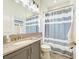 Well-lit bathroom with shower and striped curtain, gray cabinets, sink, and a neutral color palette throughout at 15525 Corona Del Mar Dr, Wimauma, FL 33598