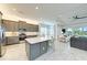 Bright kitchen with island seating, gray cabinets, and seamless flow to the living area at 15525 Corona Del Mar Dr, Wimauma, FL 33598