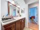 Bathroom view featuring a dark wood vanity, large mirror and doorway to the bedroom at 1599 Mcauliffe Ln, Palm Harbor, FL 34683