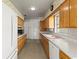 Kitchen featuring wood cabinets, laminate countertops, vintage appliances, patterned wallpaper, and white appliances at 1675 Robin Hood Ln, Clearwater, FL 33764