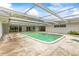 A screened in-ground pool surrounded by a concrete deck and adjacent to a building at 1675 Robin Hood Ln, Clearwater, FL 33764