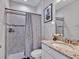 Modern bathroom with granite counter, a shower featuring grey tile and glass door with decorative grey-toned paint at 17845 Cortes Creek Blvd, Spring Hill, FL 34610