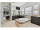 This bathroom features a large tub with a tiled surround, dark wooden cabinets, and tiled floors at 17914 Bramshot Pl, Lutz, FL 33559