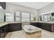 The bathroom features a large tub with a granite backsplash, dark wooden cabinets and tiled floors at 17914 Bramshot Pl, Lutz, FL 33559