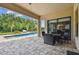 Covered patio with outdoor seating overlooking a sparkling pool and lush tropical landscaping at 17914 Bramshot Pl, Lutz, FL 33559