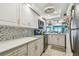 Bright kitchen featuring white cabinetry, tile backsplash and black appliances at 17980 Gulf Blvd # 505, Redington Shores, FL 33708