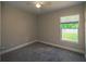 Cozy bedroom with neutral walls, plush carpet, and a bright window with verdant view at 19247 Otters Wick Way, Land O Lakes, FL 34638