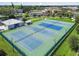 Aerial view of community tennis courts with new blue and green surface, surrounded by mature trees at 2468 Florentine Way # 26, Clearwater, FL 33763