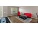 Cozy living area with hardwood floors, a bright window, and comfortable red seating at 25332 Lexington Oaks Blvd, Wesley Chapel, FL 33544