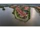 Aerial view of waterfront condos with red tile roofs surrounded by lush green trees and serene waters at 2739 Via Capri # 1011, Clearwater, FL 33764