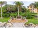 Apartment buildings amidst lush landscaping, including benches with a firepit and palm trees at 2739 Via Capri # 1011, Clearwater, FL 33764
