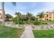 Exterior view showcasing apartment buildings amidst lush landscaping, including benches and palm trees at 2739 Via Capri # 1011, Clearwater, FL 33764