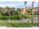 Exterior view of condo community with tropical landscaping, green grass and benches at 2739 Via Capri # 1011, Clearwater, FL 33764