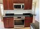 Kitchen featuring stainless steel range, built in microwave, dark wood cabinets and granite countertops at 2861 Penridge Dr, Palm Harbor, FL 34684