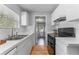 Galley kitchen featuring bright cabinets, stainless steel sink, and wood floors at 3125 W Fielder St, Tampa, FL 33611