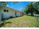 Side view of the home and fenced backyard with mature trees, and well-maintained lawn at 3305 Blythe Ave, Spring Hill, FL 34609