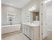 Well-lit bathroom featuring a soaking tub, a light grey vanity, and modern fixtures at 4523 Foley Grove Dr, Valrico, FL 33596