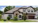 Charming two-story home with stone accents, a tile roof, a three-car garage, and manicured landscaping at 4523 Foley Grove Dr, Valrico, FL 33596