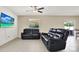 Living room with tile floors, ceiling fan and leather seating with a large television at 5067 Sable Chime Dr, Wimauma, FL 33598