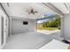 An open patio with a fan, a mounted television, and views of a fenced-in yard with tropical plants at 526 62Nd Ne Ave, St Petersburg, FL 33702