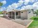 Tan home featuring brick pavers, a screened in lanai, a small yard, and a stone bed at 5470 Bayshore Dr, Seminole, FL 33772