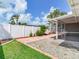 Beautiful backyard featuring brick pavers, a white fence, tropical foliage, and a screened in lanai at 5470 Bayshore Dr, Seminole, FL 33772