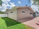 A tan home featuring a brick paver patio with a small grassy lawn at 5470 Bayshore Dr, Seminole, FL 33772