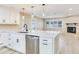 Open kitchen with stainless steel dishwasher, island with sink, and a stone fireplace in view at 5470 Bayshore Dr, Seminole, FL 33772