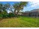 Beautiful backyard with green lawn, mature trees, a fire pit, and a screened-in pool area at 5825 Terncrest Dr, Lithia, FL 33547