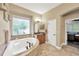 Bathroom with a luxurious tub, tiled floors, vanity, and access to the main bedroom at 5825 Terncrest Dr, Lithia, FL 33547